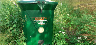 Kompostori pihan laidalla, heinikkoa ympärillä