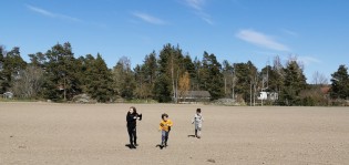 Lapset juoksevat kynnetyllä pellolla